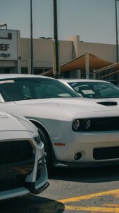 White Dodge Challenger in a car dealership parking lot during the day.